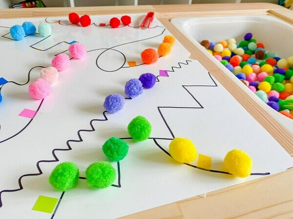 Des Languettes adhésives Post-it® et des pompons de couleurs assorties placés sur diverses parties des lignes sur la Surface Flex Write Post-it®.