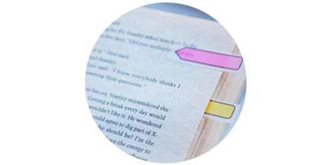 arrow flags being used in a book to mark a sentence.
